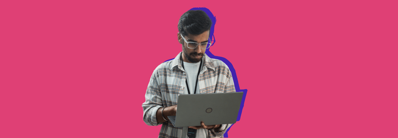 A man in glasses and a checked shirt using a laptop, set against a red background.