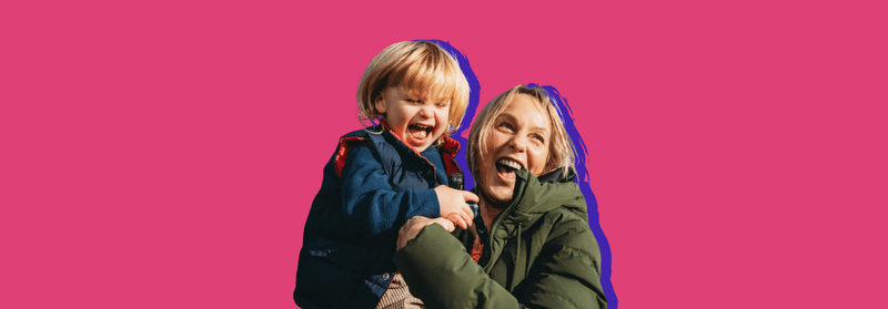 Two smiling children hugging, set against a pink background.