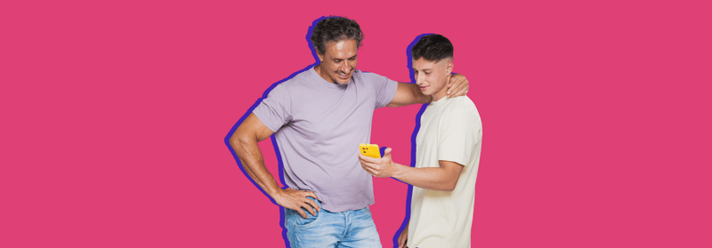 Two young men standing side by side, one glancing at his phone, set against a blue background.