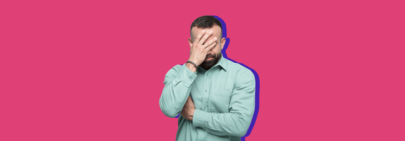 A man covering his face with one hand in frustration, set against a blue background.