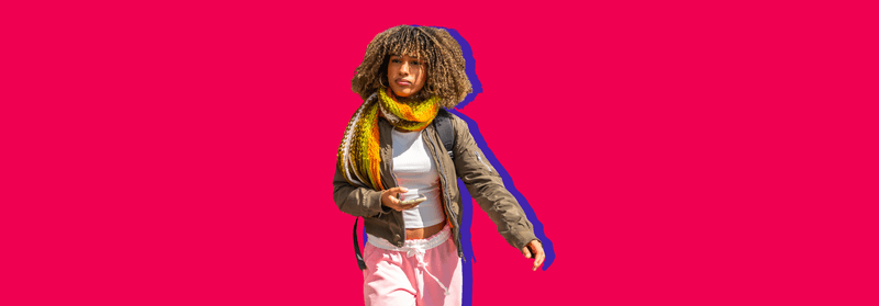 A woman with curly hair and a yellow scarf holding a coffee cup, set against a red background.