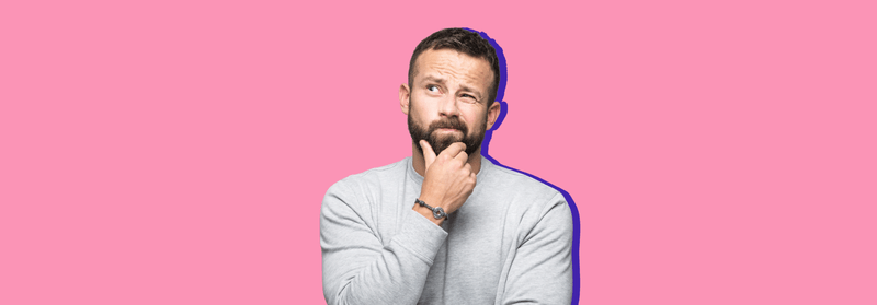 A bearded man resting a hand on his chin in thought, set against a pink background.