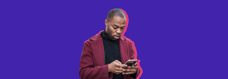 A Black man in a burgundy jacket looking down at his smartphone, set against a purple background