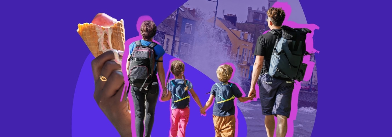 Parents and two children walking hand in hand down a seaside street, with a hand holding an ice cream in the foreground