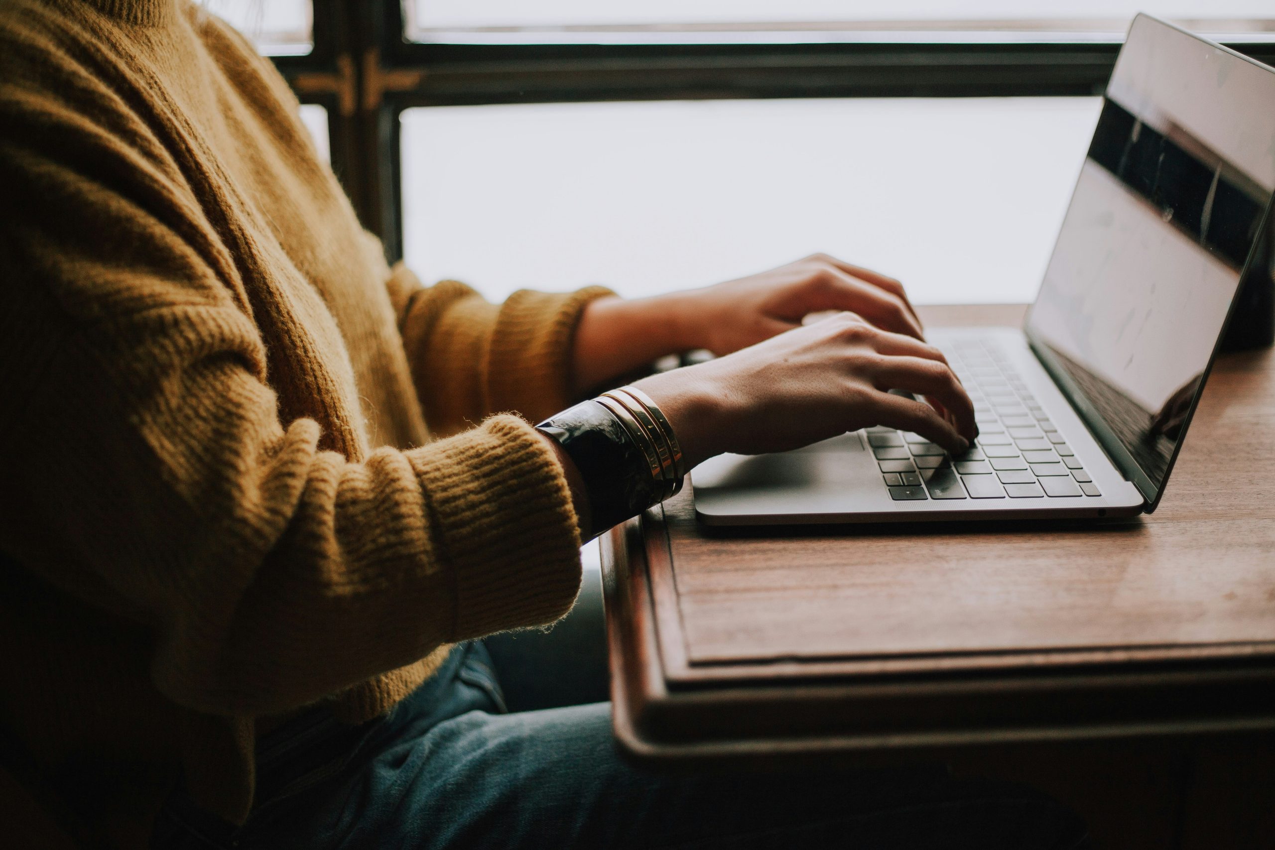 A person typing on a laptop at a desk, representing the work of a consumer insights manager analyzing data, researching customer behaviour, and turning insights into business strategy.