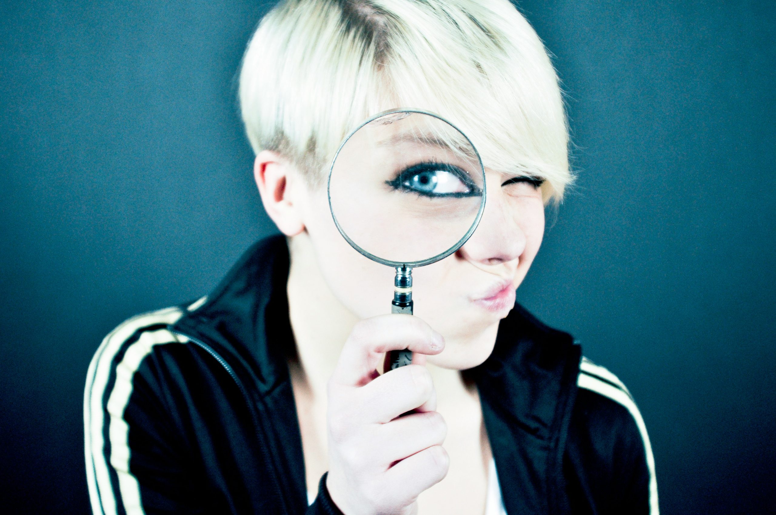 A person holding a magnifying glass up to one eye while examining something closely, symbolizing the importance of consumer insight in helping businesses better understand customer behaviour, needs, and decision-making.
